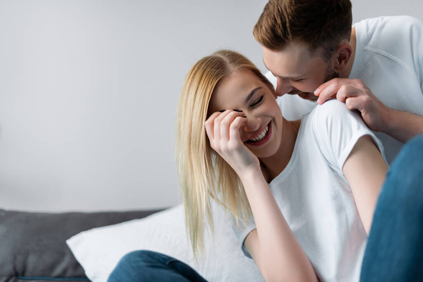 selective focus of cheerful couple laughing in bedroom  - Zdjęcie, obraz