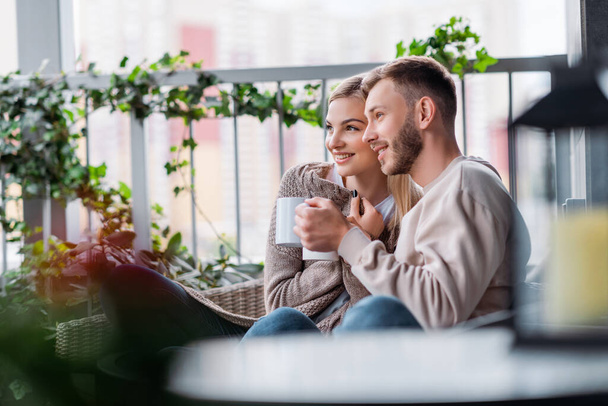 selective focus of happy couple holding cups while sitting outside  - Valokuva, kuva