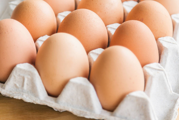 Φρέσκα αυγά σε σχάρα αυγών πάνω σε ξύλινο τραπέζι. Ετοιμάστε αυγά κοτόπουλου για μαγείρεμα ή φούρνο σε ρουστίκ ξύλινο τραπέζι. Κλείσιμο με επιλεκτική έννοια εστίαση φρέσκα αυγά με χώρο αντίγραφο για φόντο ή ταπετσαρία. - Φωτογραφία, εικόνα