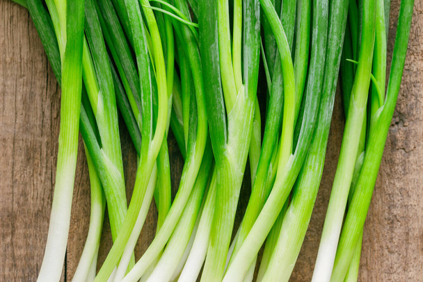 Fresh spring onion on rustic wood table. Close up callions or spring onion on wood plank in top view flat lay. Prepare spring onion for cooking. Food and vegetable concept for background or wallpaper. - Photo, Image