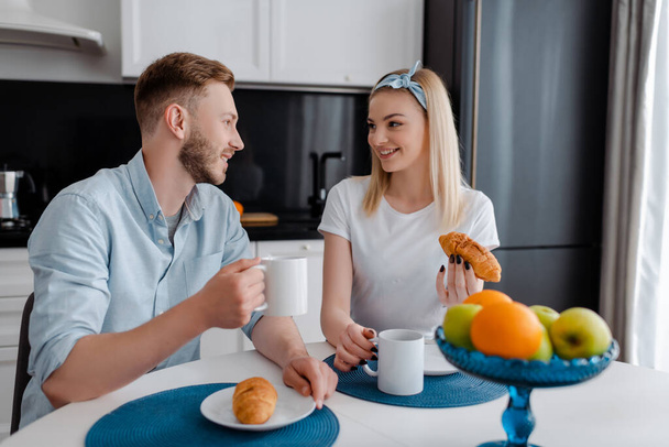 feliz mujer y hombre mirándose el uno al otro cerca de sabroso desayuno
  - Foto, Imagen