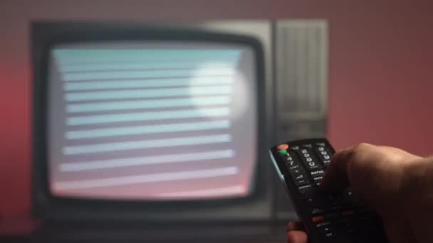 Alte Oldtimer-Fernseher auf dem Auktionsmarkt, Nahaufnahme einer Hand, die eine Fernbedienung hält und Knöpfe für wechselnde Sender drückt. Antiker Retro-Fernseher mit blinkendem Bildschirm auf dunkelrotem Hintergrund - Filmmaterial, Video