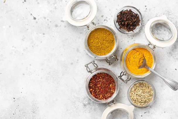 Spices and condiments in glass jars on a light gray table. Spices close-up with space for text. The view from the top - 写真・画像