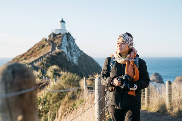 Hermoso turista asiático tomar alguna foto en Nugget Point, Dunedin, Nueva Zelanda. Jóvenes viajeros asiáticos disfrutan de caminar por la mañana a lo largo de la costa de Nueva Zelanda. Imagen de estilo de vida con paisaje natural
. - Foto, Imagen