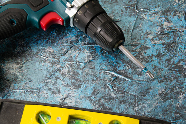 Screwdriver and level on blue concrete background. Concept advertising construction companies - Photo, Image