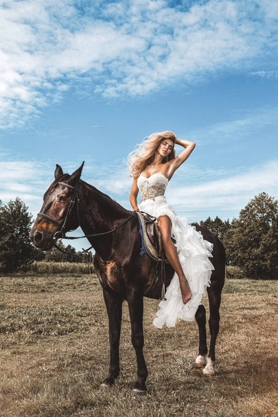 Portrait of a dark horse and woman. Beautiful glamour woman with a horse. Portrait of a beauty blonde bride in wedding dress with horse. - Foto, immagini