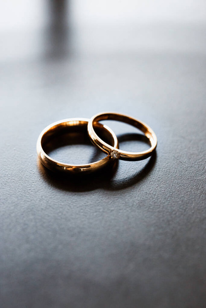 Svatební prsteny ze žlutého zlata. Vyložené diamanty. Na homogenním povrchu. - Fotografie, Obrázek