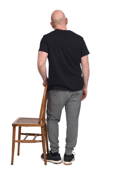 вид сзади на человека, стоящего со стулом на белом фоне - Фото, изображение