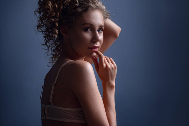 Tender portrait of a woman with curly hair in a room. Beautiful alluring young woman in sexy lingerie posing indoor. idea and concept of femininity, tenderness, spring and sexuality - Foto, immagini