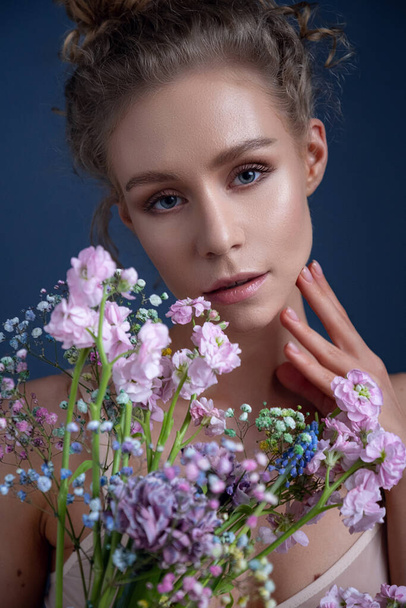 Tender portrait of a woman with curly hair in a room. delicate bouquet of spring flowers. idea and concept of femininity, tenderness, spring and sexuality - Photo, Image
