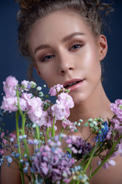 Tender portrait of a woman with curly hair in a room. delicate bouquet of spring flowers. idea and concept of femininity, tenderness, spring and sexuality - Foto, Bild