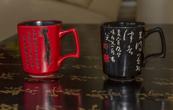 Dos tazas rojas y negras decoradas con caligrafía china
 - Foto, imagen