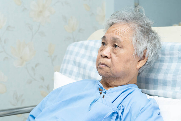 Azji starsza lub starsza pani pacjent siedzi i martwić covid-19 na łóżku w szpitalu pielęgniarskim - Zdjęcie, obraz