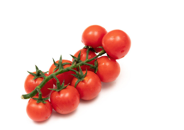 A branch of red cherry tomatoes on a white background. Small and juicy vegetable is rich in vitamins and trace elements. Healthy food. Fresh and organic vegetables. Raw food. - Zdjęcie, obraz