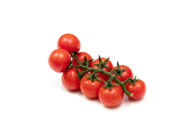 A branch of red cherry tomatoes on a white background. Small and juicy vegetable is rich in vitamins and trace elements. Healthy food. Fresh and organic vegetables. Raw food. - Valokuva, kuva