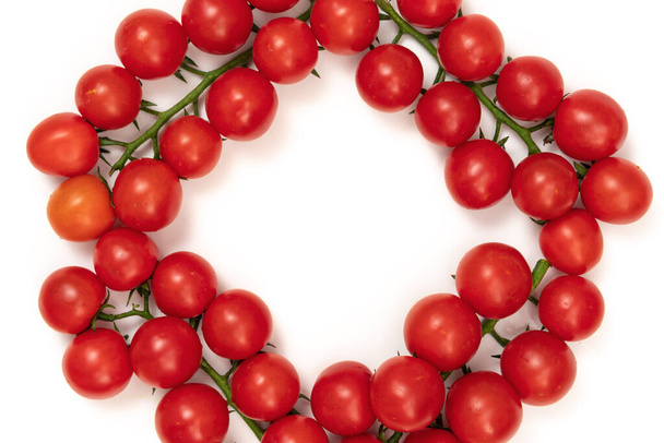 A branch of red cherry tomatoes on a white background. Small and juicy vegetable is rich in vitamins and trace elements. Healthy food. Fresh and organic vegetables. Raw food. - Фото, изображение