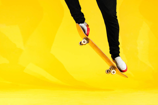 Skateboarder realizar truco de skate - ollie en concreto. Estudio de tiro de atleta olímpico practicando salto sobre fondo amarillo, preparándose para la competición. Deportes extremos, cultura juvenil
 - Foto, imagen