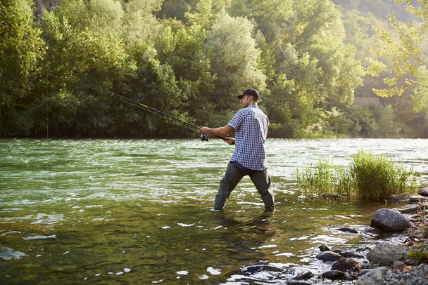 Fischer, der in der Nähe des Flusses steht und Angelrute hält - Foto, Bild