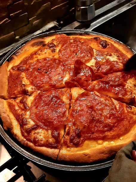 a házi készítésű pizza hangulatos képe fűszeres szalámival, paradicsommal és mozzarellával - Fotó, kép