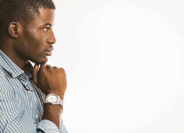 Pensive African American businessman touches his chin with hand with luxury wristwatch. Creative guy generating of idea on white background. Copy space at right. Contemplation concept. Toned image - Foto, Imagem