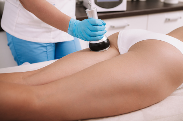 Cropped shot of a woman getting rf-lifting treatment on the back of her legs by professional beautician. Cosmetologist performing rf-lifting therapy for female client - Foto, Imagen
