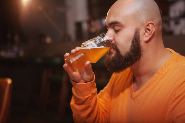 Primo piano di un uomo barbuto che si diverte a bere deliziosa birra fresca al pub, copia lo spazio
 - Foto, immagini