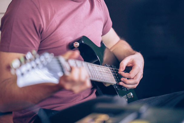 Close up hand of young man playing on a professional, black electric guitar, instrument muzyczny, rozrywka, styl życia - Zdjęcie, obraz