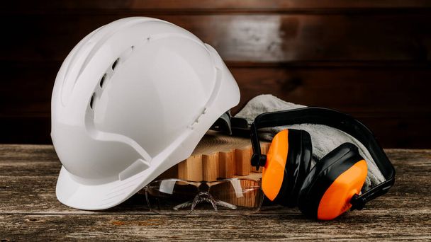 Λευκό κράνος και πορτοκαλί ακουστικά σε ξύλινο φόντο. Προστατευτική ποδιά κεφαλής - Φωτογραφία, εικόνα