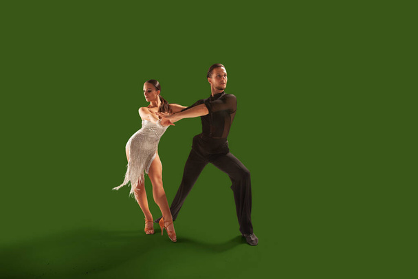 Пара танцюристів виконують латинський танець на зеленому тлі екрану
. - Фото, зображення
