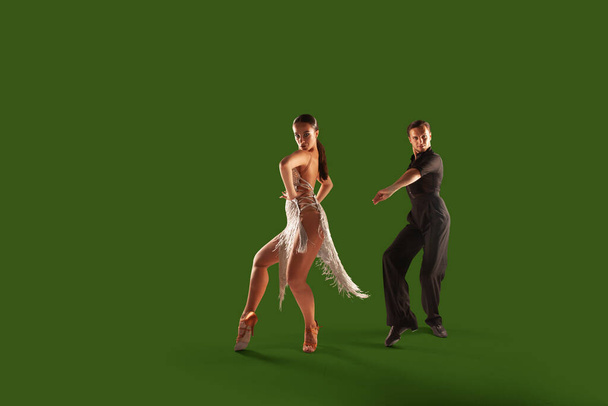 Paartänzer führen lateinamerikanischen Tanz auf grünem Hintergrund auf. - Foto, Bild