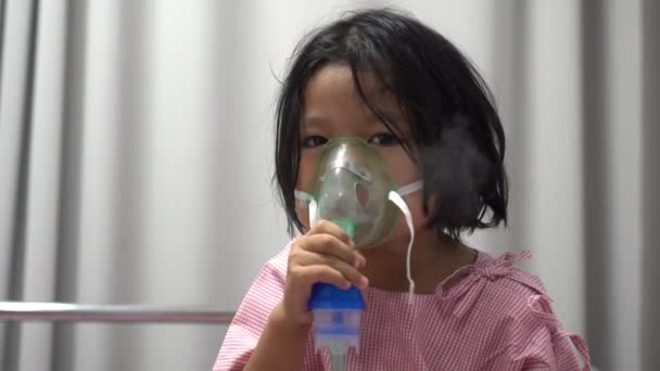 Ragazzina asiatica che ha una maschera di ossigeno e respira attraverso un nebulizzatore all'ospedale. Concetto di bronchite, respiratorio e trattamento medico. - Filmati, video
