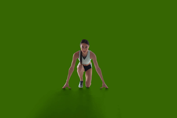 Mujer atleta en ropa deportiva sobre fondo de pantalla verde
. - Foto, Imagen
