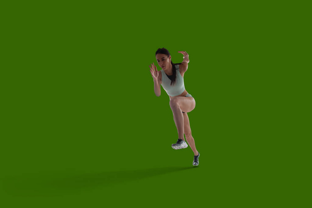 Mujer atleta en ropa deportiva sobre fondo de pantalla verde
. - Foto, imagen