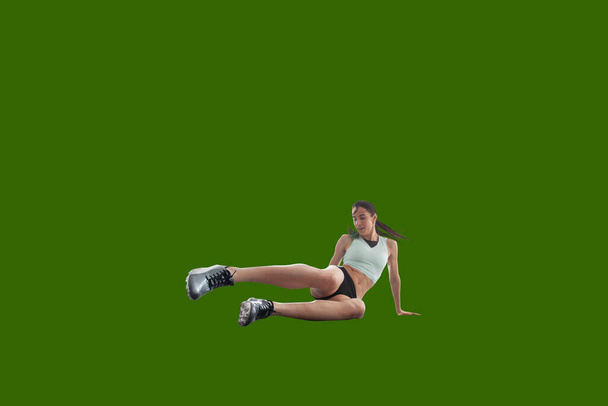 Αθλητική γυναίκα σε αθλητικά ρούχα σε πράσινο φόντο οθόνη. - Φωτογραφία, εικόνα