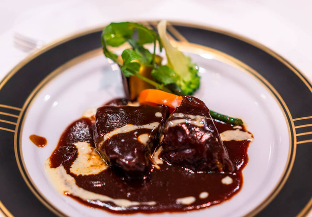 Ranskan tärkein ruokalaji muhennos naudanlihaa bourguignon haudutetaan punaviinikastiketta vihanneksia kuten porkkanat valkoinen ja musta illallinen lautasella kultainen vanteen. - Valokuva, kuva