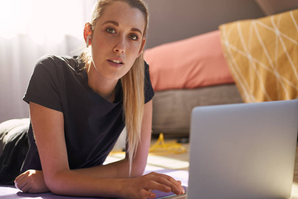 Молода жінка бере участь в онлайн-класі з фітнесу перед ноутбуком
. - Фото, зображення