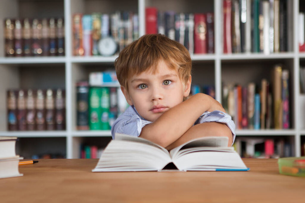 bambino ragazzo studiare a casa. homeschooling, apprendimento a distanza. uno scolaro legge un libro seduto a un tavolo
 - Foto, immagini