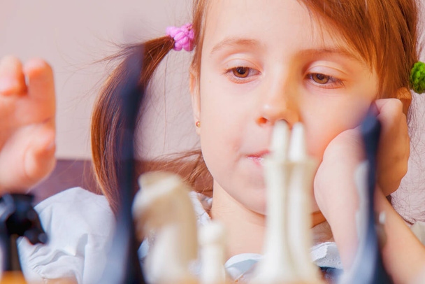 チェスをしている小さな美しい子供の女の子を閉じます。手と指に焦点を当てる. - 写真・画像