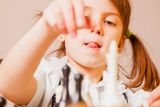 Investing in the future: training and education of the future chess champion. Beautiful child girl learns to play chess. Sport, development, childhood, success, wunderkind concept - Photo, Image