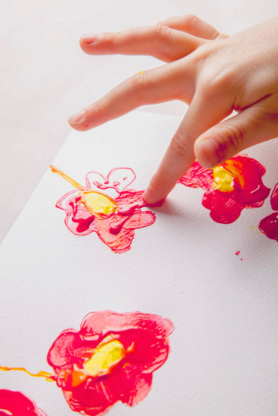 子供の女の子はカラフルな手と指で花を描く   - 写真・画像