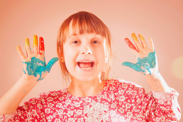 Веселе проведення часу, мистецтво і концепція бадьорість. Барвисті пофарбовані руки в красиву щасливу молоду дівчину. Забавна експресія обличчя дитини
. - Фото, зображення