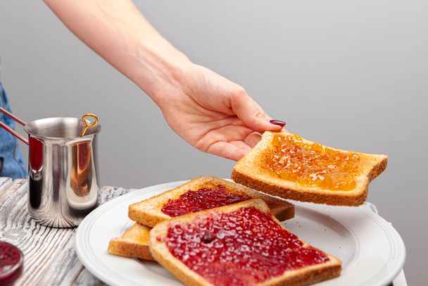 Female hands preparing toasts with fruit jam - Zdjęcie, obraz