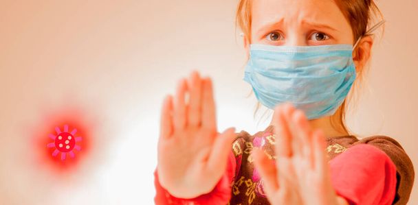 Stop virus- en epidemische ziekten. Bang klein meisje met een blauw medisch beschermend masker met gebaar stop. Gezondheidsbescherming en preventie tijdens griep en besmettelijke uitbraak - Foto, afbeelding