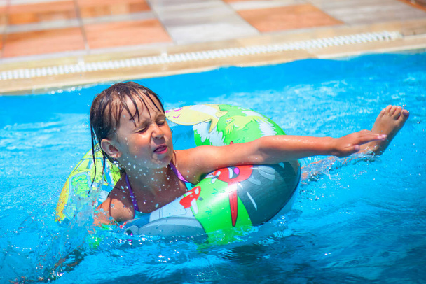 Vtipná dynamická fotografie krásné holčičky v bazénu v letovisku. Letní dovolená a šťastný bezstarostný koncept dětství. - Fotografie, Obrázek