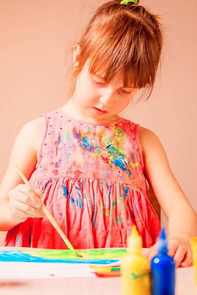 Κοντινό πλάνο χαριτωμένο κοριτσάκι κρατώντας πινέλα μπογιάς. Τέχνη και εκπαίδευση έννοια. Κάθετη εικόνα. - Φωτογραφία, εικόνα