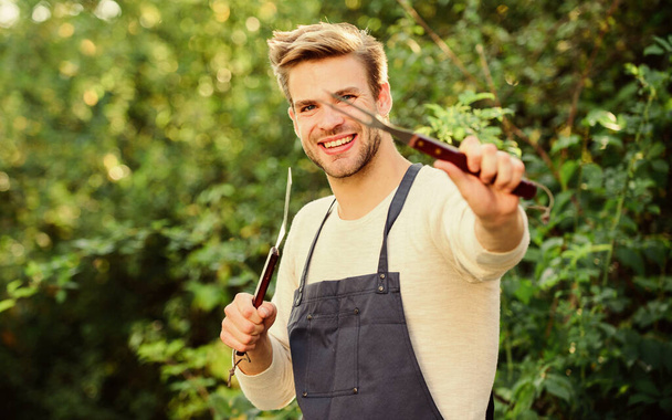 Tools for roasting meat outdoors. Barbeque party. Cooking burgers. Picnic concept. Bbq chef. Handsome guy cooking food. Man hold barbeque equipment. Grilling food. Barbecue utensils. Summer weekend - Foto, Imagem