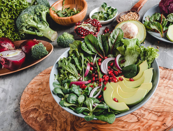 Salada fresca saudável com abacate, verduras, rúcula, espinafre, romã em placa sobre fundo cinza. Alimentos veganos saudáveis, comer limpo, dieta, vista superior
 - Foto, Imagem