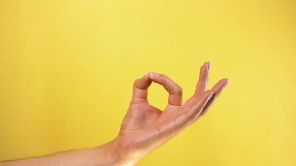 male hand showing OK gesture isolated on yellow background - Filmagem, Vídeo
