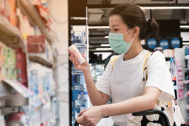 Азиатка в футболке с желтой сумкой носить хирургическую маску, чтобы защитить Covid-19 в супермаркете, Новый нормальный образ жизни
 - Фото, изображение