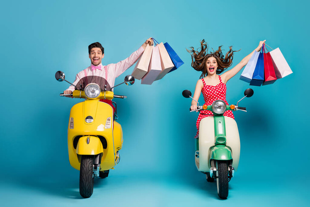 Full size photo positive two people man woman driver rider biker ride scooter motor bike shopping center buy bags enjoy off-sales wear red dotted dress shirt isolated blue color background - Zdjęcie, obraz